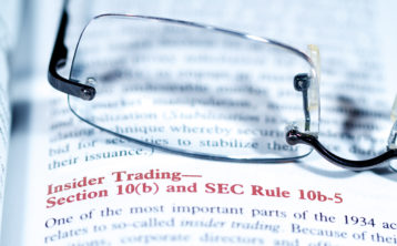 Glasses on top of book talking about insider trading