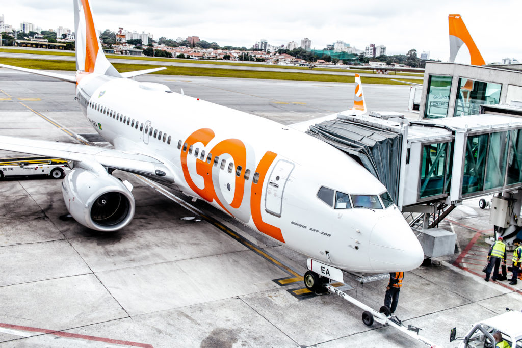A photo of a GOL plane at the airport as passengers embark and disembark.
