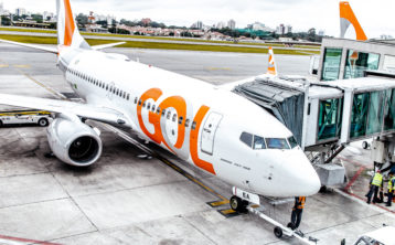 A photo of a GOL plane at the airport as passengers embark and disembark.
